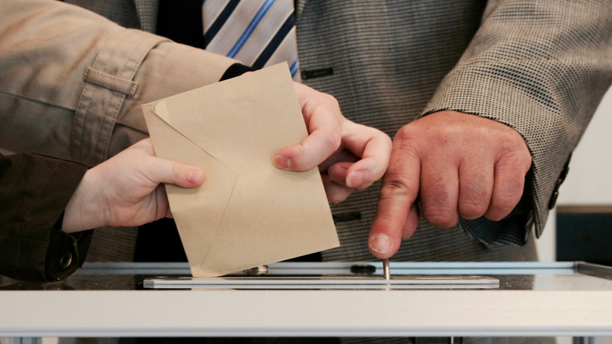 Una persona mete el sobre con su voto en la urna