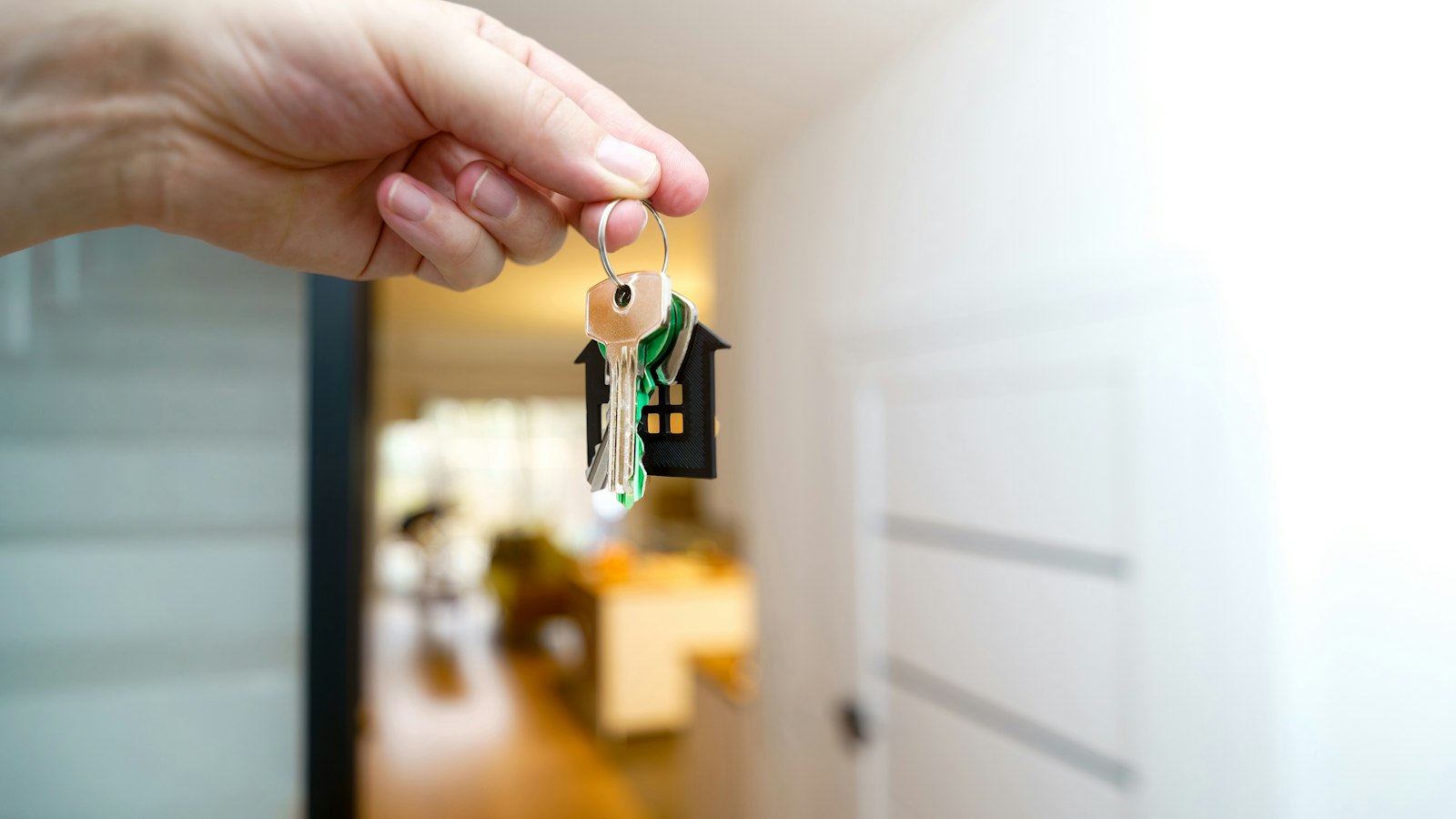 Una mano sostiene las llaves de un piso turístico con un llavero en forma de casa